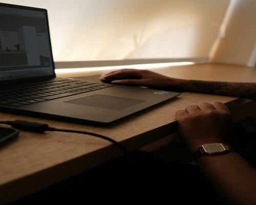 A person typing on a laptop with comfortable ambient light in a modern home office